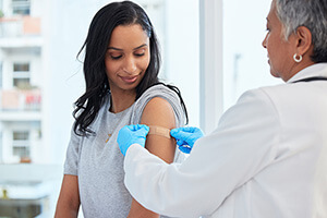 A female doctor is administering a flu shot to a smiling woman at urgent care